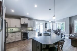 The Golden Locust Open-concept kitchen and dining area featuring a black island, white cabinets, and large windows with a view.
