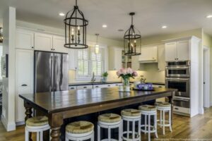 Heron Gate | Photography: © Daniel Vaughan (vaughangroup.ca) Farmhouse kitchen featuring a dark wood island, white cabinetry, and two large black birdcage-style chandeliers.