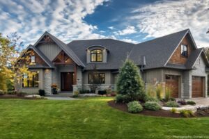 Craftsman-style home with stone and wood siding, featuring gabled roofs and a well-manicured front lawn.