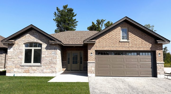 Exterior of house with brown brick and an attached garage with a gravel driveway