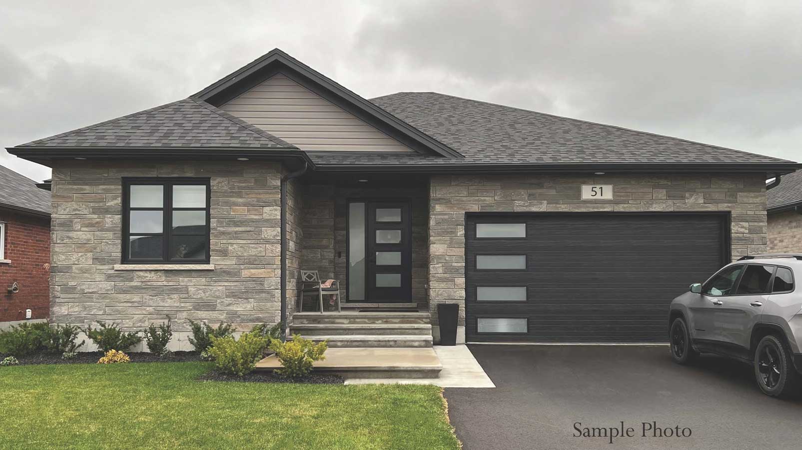 Exterior of grey stone house with front steps and attached garage