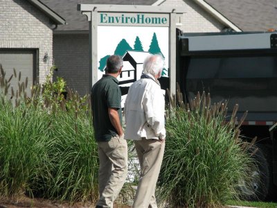 Senior father and son walking outside past a home sign that says "EnviroHome"