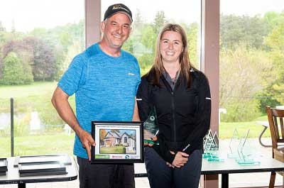 Smiling man and woman while man holds award and picture of a house in a frame