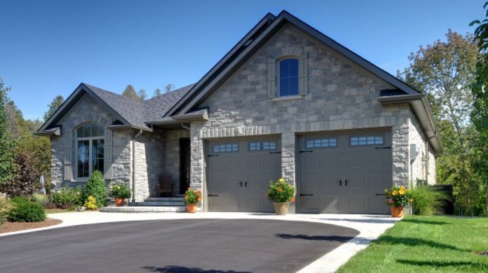 Landscaped stone home with attached two car garage