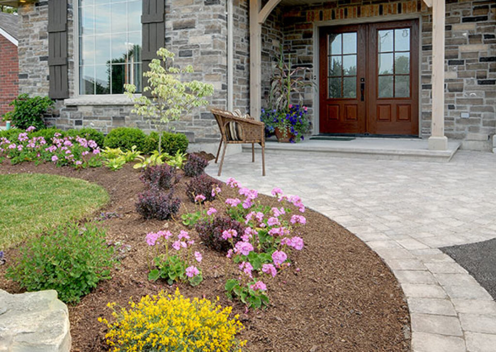 A landscaped curved garden with flowers and greenery at front entrance of home