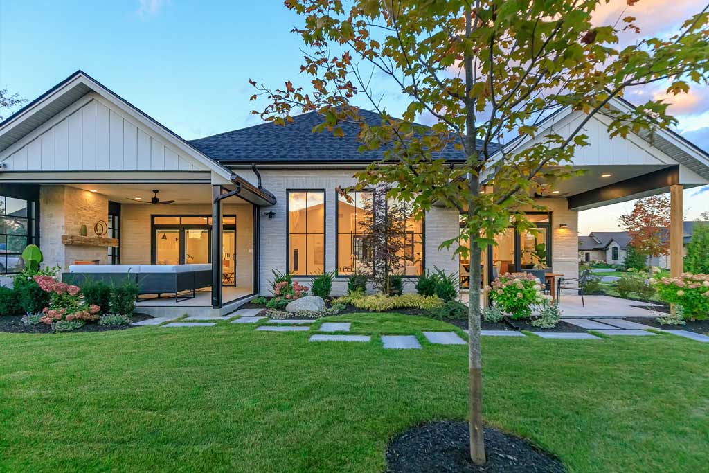 A modern house with two covered patio areas connected by stone patio blocks and manicured gardens