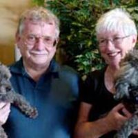 Senior woman and man smiling for photo while each hold a small dog in their arms