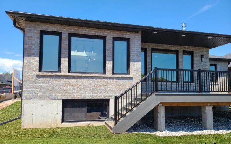 Grey stone home with deck and wide windows