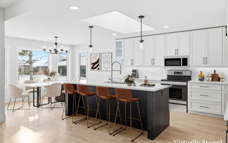 A modern kitchen with white cabinets and clear globe lights hang down overtop of the island with brown stools