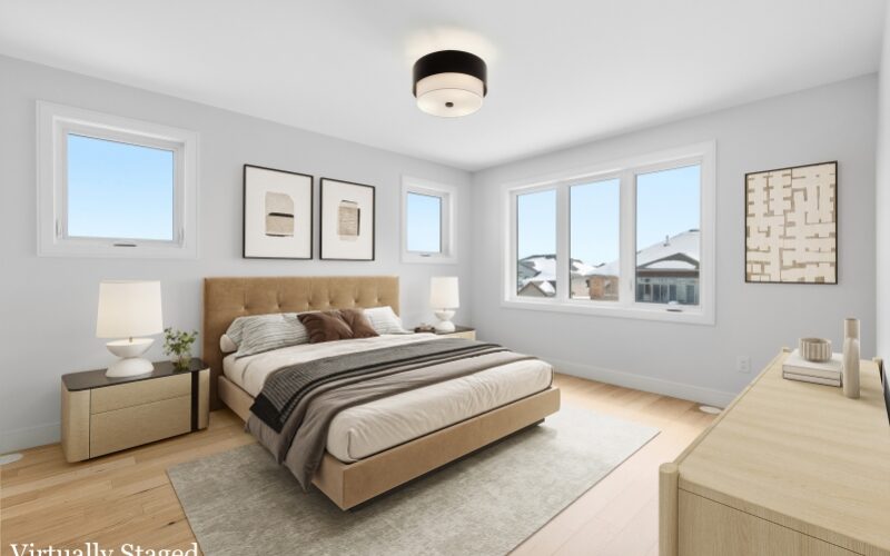 A symmetrical bedroom with bedside tables and lamps, windows and two hanging pictures. A wall with 3 panel window is beside the bed.