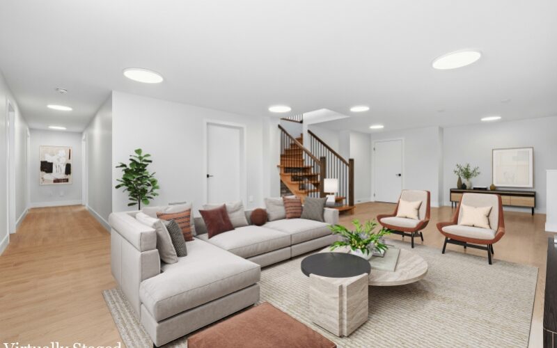 Living room with grey area rug and an L-shaped couch and modern furniture accents